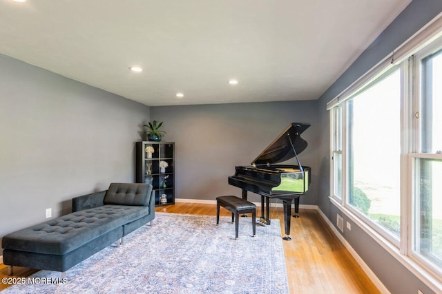 living area with recessed lighting, baseboards, a wealth of natural light, and light wood-style flooring