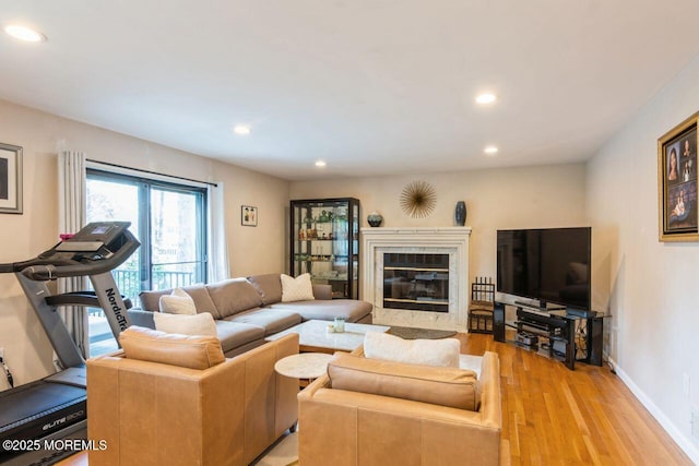 living area with recessed lighting, baseboards, light wood-style flooring, and a fireplace