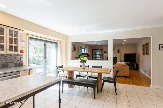 dining room featuring baseboards, recessed lighting, light tile patterned floors, and a fireplace
