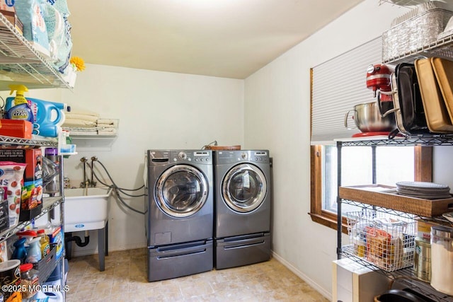 clothes washing area with laundry area, baseboards, and washer and dryer