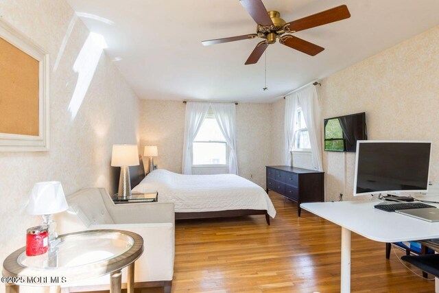 bedroom with wallpapered walls and wood finished floors