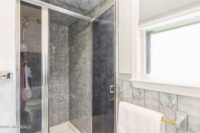 full bath featuring tile walls, a stall shower, and toilet