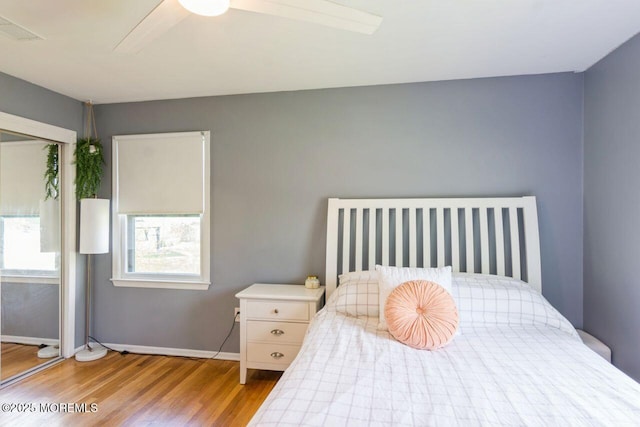 bedroom with a ceiling fan, baseboards, visible vents, and wood finished floors