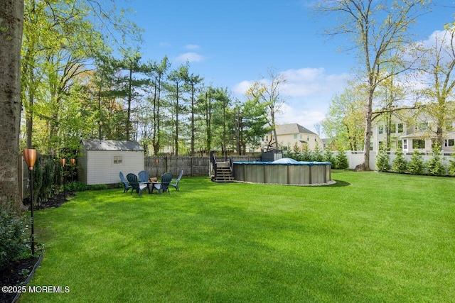 view of yard with a storage unit, a fenced backyard, an outbuilding, and a fenced in pool