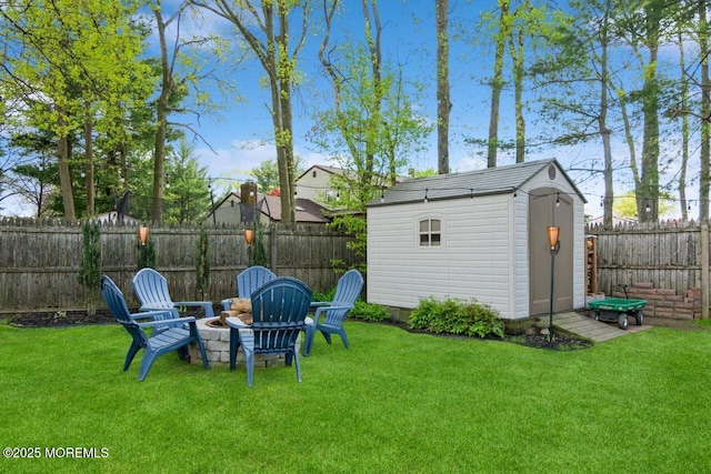 view of yard with an outdoor structure, a fenced backyard, a fire pit, and a shed