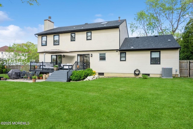 rear view of property featuring fence, a wooden deck, a chimney, a patio area, and a lawn