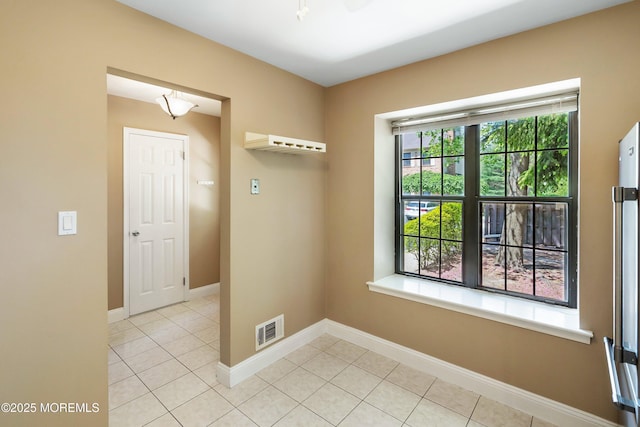 empty room with light tile patterned floors, baseboards, and visible vents