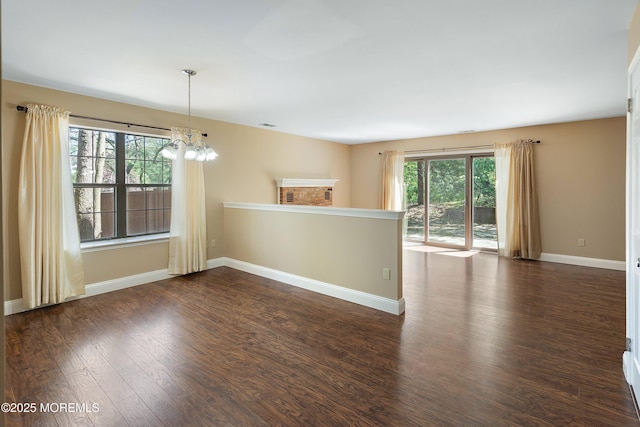spare room featuring an inviting chandelier, dark wood finished floors, and baseboards