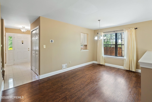 unfurnished dining area with a chandelier, visible vents, plenty of natural light, and wood finished floors
