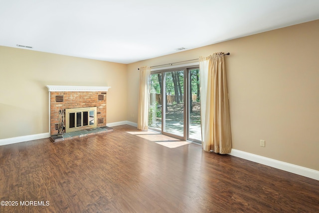 unfurnished living room featuring baseboards, visible vents, and wood finished floors