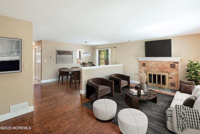 living room with visible vents, wood finished floors, baseboards, and a fireplace