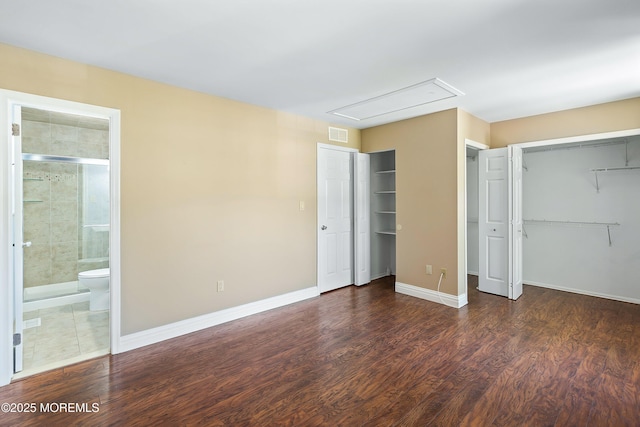 unfurnished bedroom featuring attic access, visible vents, multiple closets, and wood finished floors