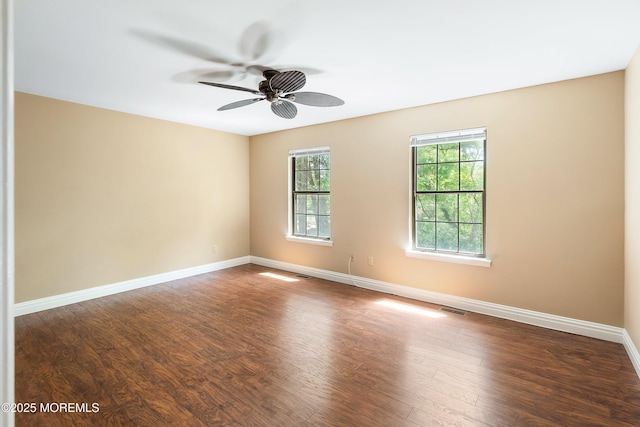 spare room featuring baseboards, dark wood finished floors, ceiling fan, and visible vents