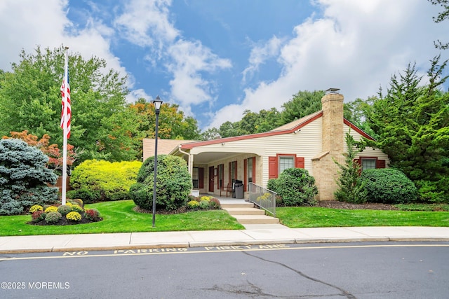 view of front of property featuring a chimney, a front yard, and a porch