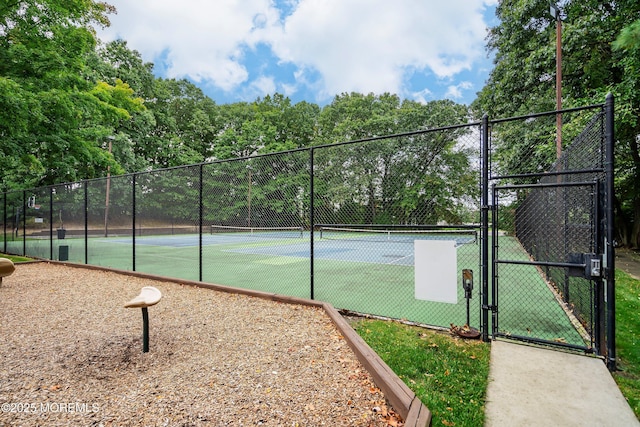 view of tennis court featuring fence and a gate