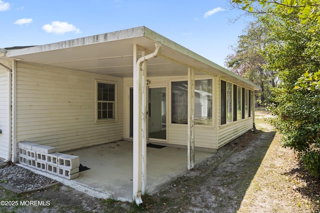 view of property exterior with a patio and a sunroom