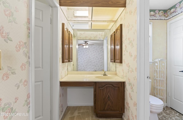 bathroom featuring vanity, a ceiling fan, toilet, and wallpapered walls