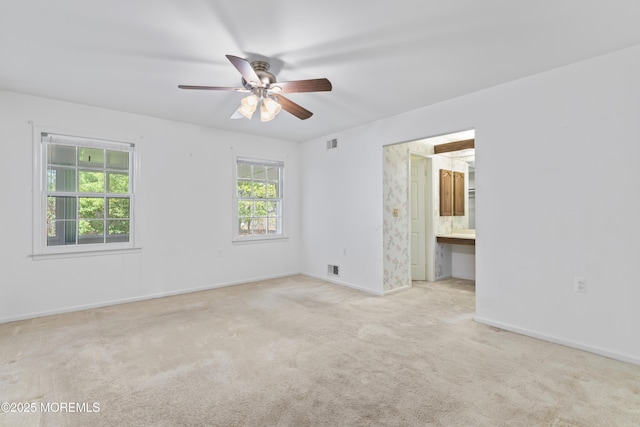 carpeted spare room with baseboards, a ceiling fan, and visible vents
