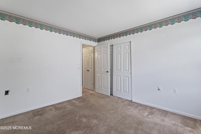 unfurnished bedroom with baseboards, carpet flooring, and a closet