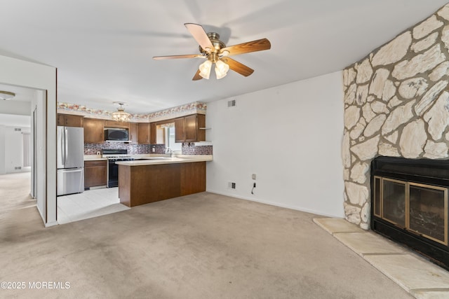 kitchen featuring gas stove, light countertops, freestanding refrigerator, a peninsula, and open floor plan