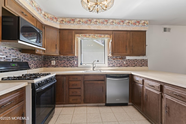 kitchen featuring stainless steel dishwasher, light countertops, a sink, backsplash, and gas stove