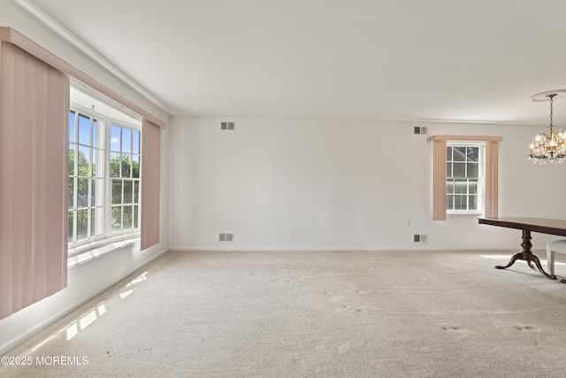 empty room featuring carpet floors, baseboards, a notable chandelier, and visible vents