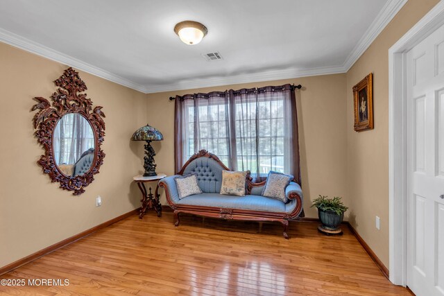 living area featuring visible vents, ornamental molding, light wood-style flooring, and baseboards
