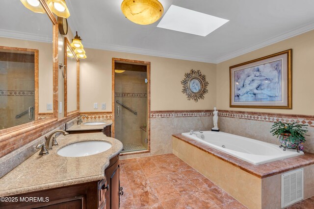 full bath featuring visible vents, tile walls, a shower stall, a sink, and a skylight