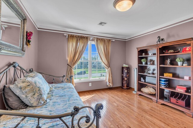 bedroom with crown molding, baseboards, visible vents, and wood finished floors
