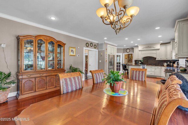 dining space featuring crown molding, wood finished floors, baseboards, an inviting chandelier, and recessed lighting