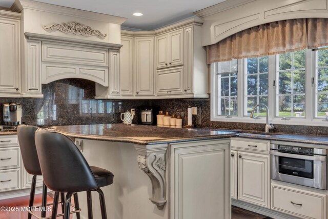 kitchen featuring a sink, a kitchen breakfast bar, tasteful backsplash, and oven