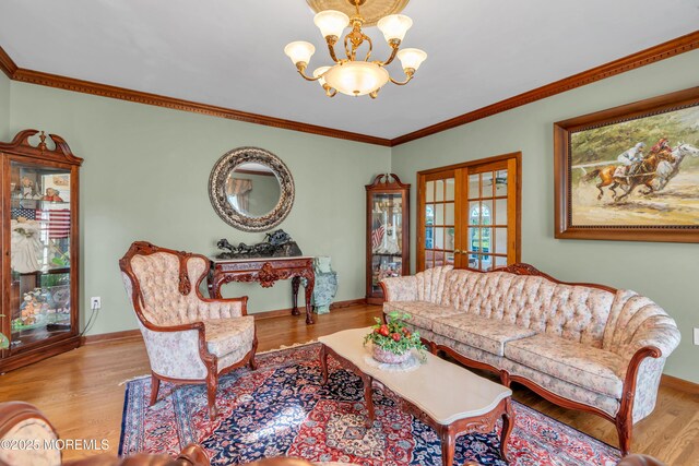 living room featuring ornamental molding, wood finished floors, baseboards, a chandelier, and french doors