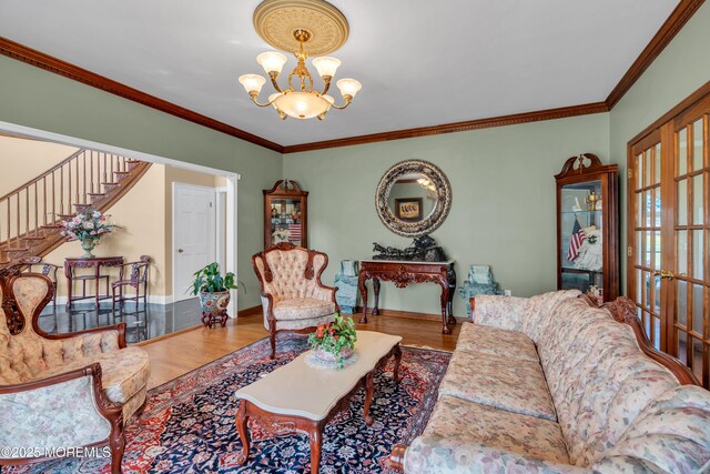 living area with baseboards, ornamental molding, wood finished floors, and a notable chandelier