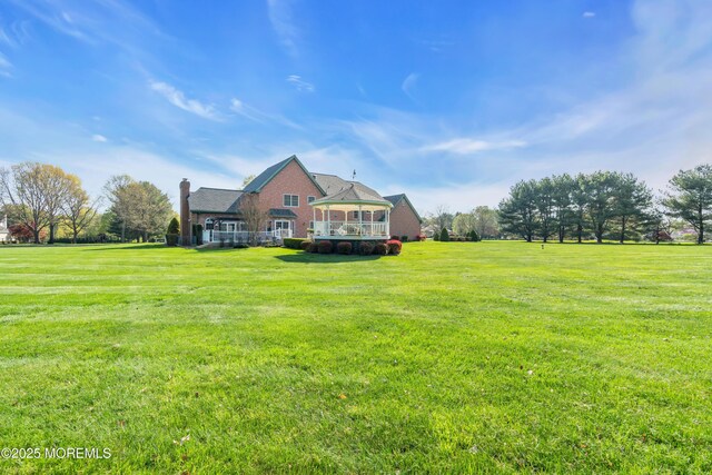 exterior space featuring a lawn, brick siding, and a gazebo