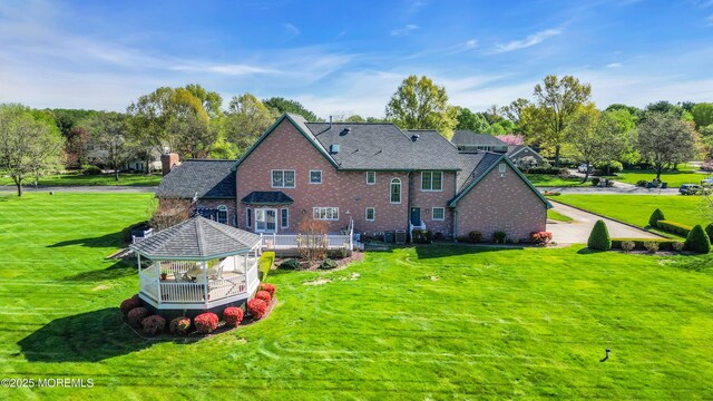 back of house with a gazebo, a yard, a deck, and brick siding