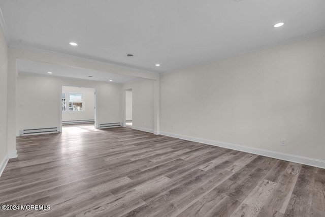 unfurnished living room featuring crown molding, baseboards, baseboard heating, and wood finished floors