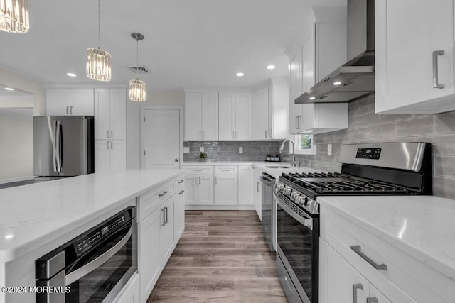 kitchen with a sink, visible vents, wall chimney exhaust hood, a chandelier, and appliances with stainless steel finishes
