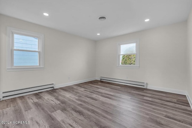 unfurnished room featuring visible vents, wood finished floors, and baseboard heating