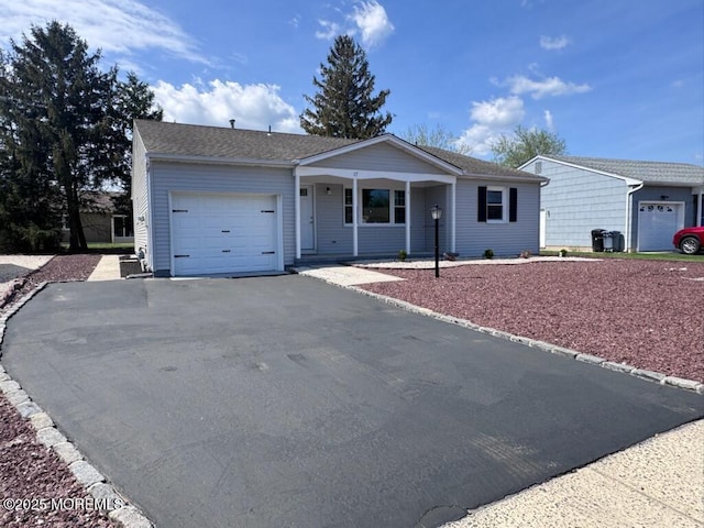 single story home with a porch, a garage, and aphalt driveway