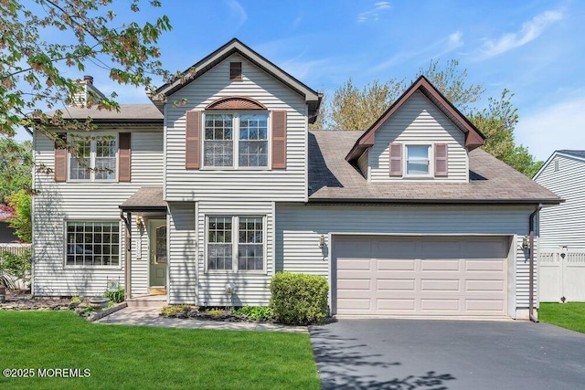 traditional-style home featuring fence, driveway, roof with shingles, and a front yard