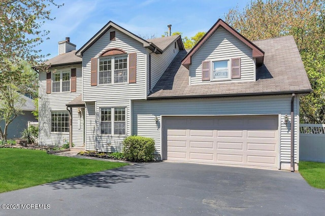 view of front of property with a chimney, roof with shingles, driveway, and a front yard
