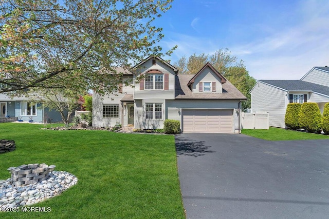 traditional-style house featuring fence, a front yard, a garage, and aphalt driveway