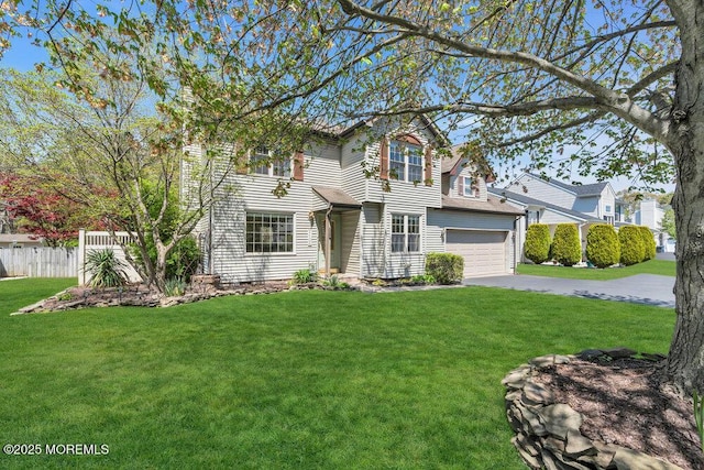 traditional home with an attached garage, fence, driveway, and a front lawn