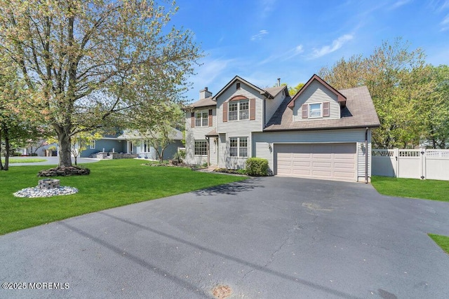 colonial home featuring a garage, aphalt driveway, fence, a front yard, and a chimney