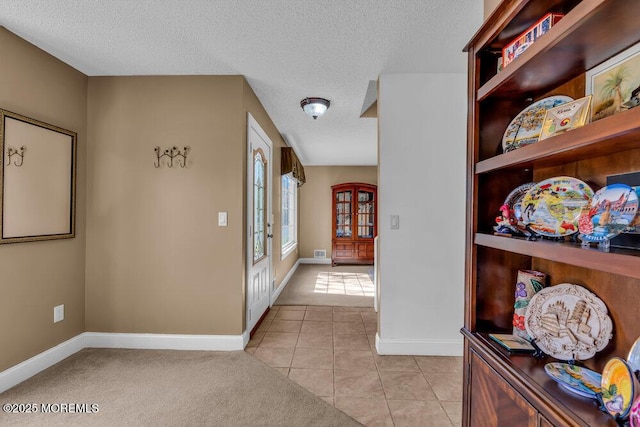entrance foyer featuring baseboards, a textured ceiling, and light tile patterned floors