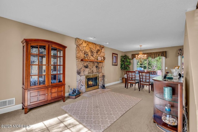 living area featuring a chandelier, a stone fireplace, carpet, baseboards, and visible vents