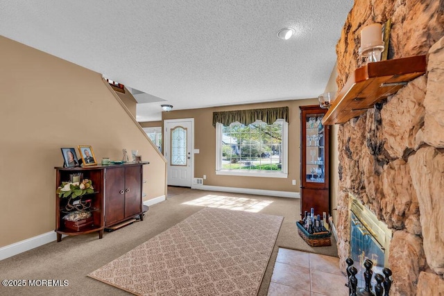 carpeted foyer entrance with baseboards and a textured ceiling