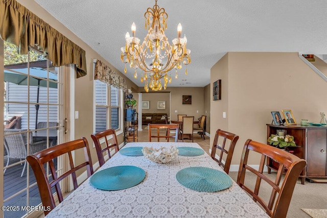 dining space with carpet floors, a textured ceiling, baseboards, and a chandelier