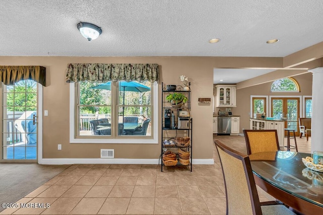 dining space with visible vents, a textured ceiling, light tile patterned flooring, and a wealth of natural light
