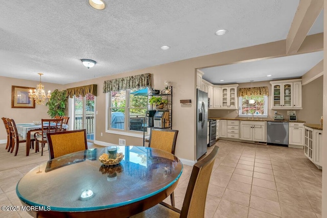 dining space with a healthy amount of sunlight, light tile patterned floors, and an inviting chandelier